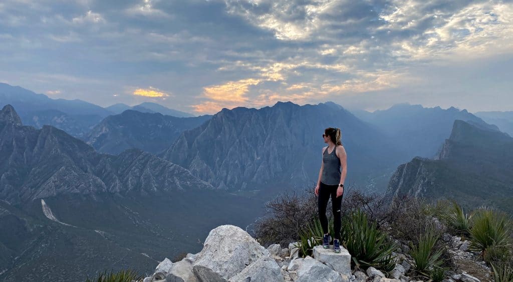 A hiker standing on the summit of Pico Horcones, overlooking the canyon of La Huasteca.