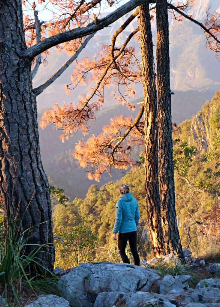 A hiker looking out over the mountains at sunrise near the summit of Puerto Gringo, Santiago.