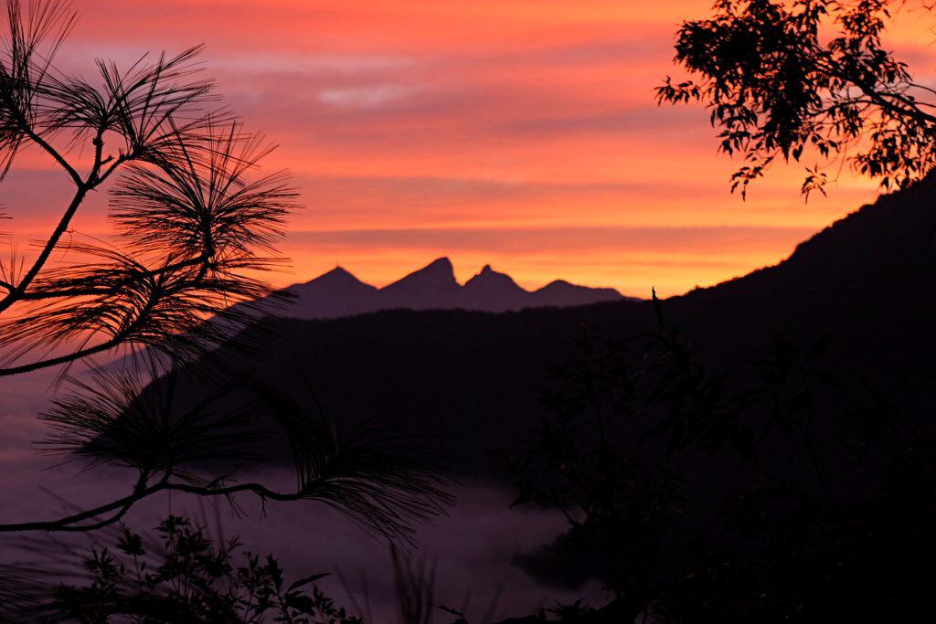 A glowing orange sky with the silhouette of cerro de la silla in the background.