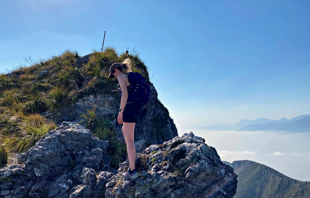Hiker navigating an exposed rocky ridge near the summit of Pico Norte, Cerro de la Silla, Monterrey